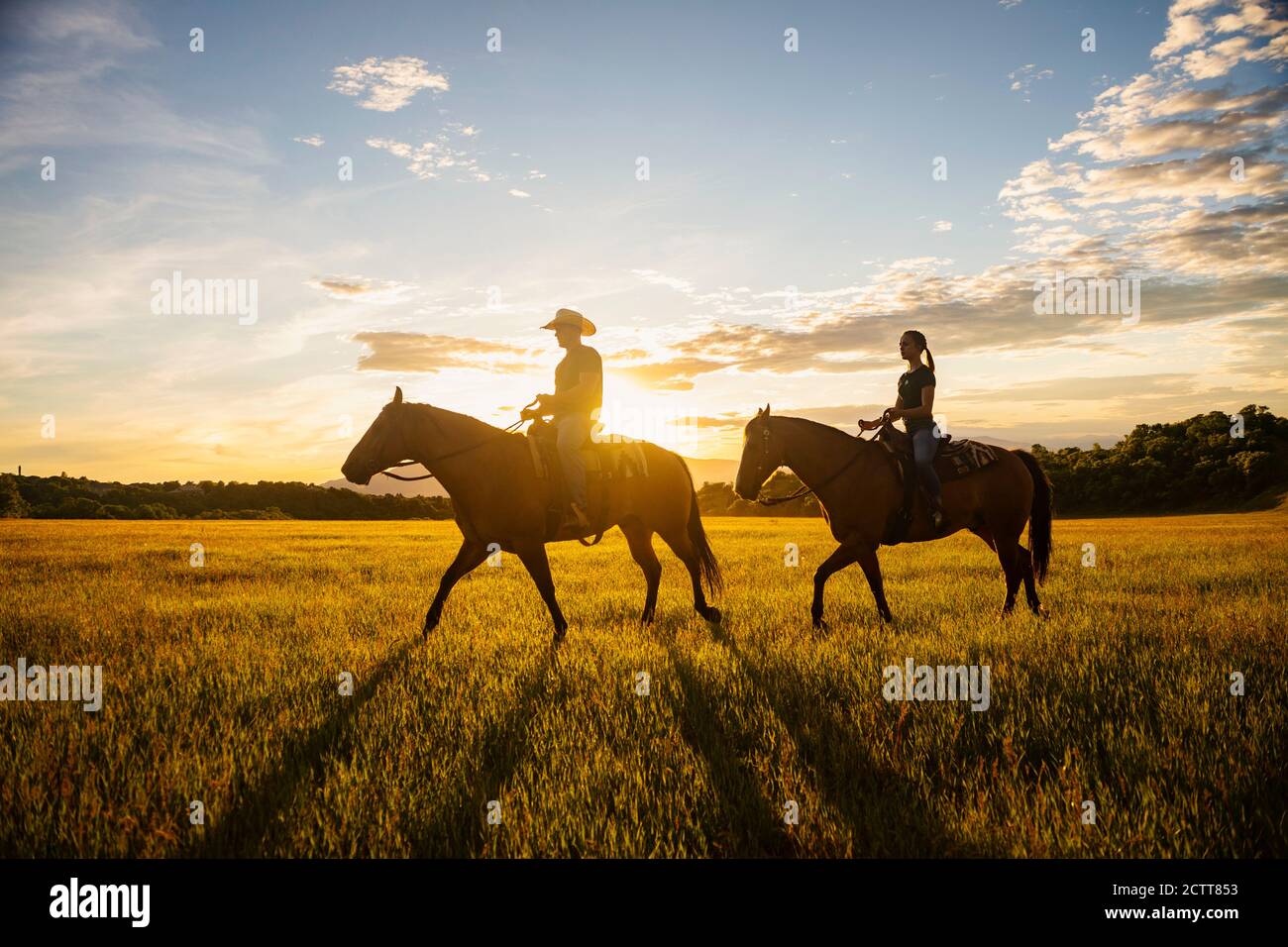 Usa, Utah, Salem, Padre e hija (14-15) montando caballos al atardecer Foto de stock