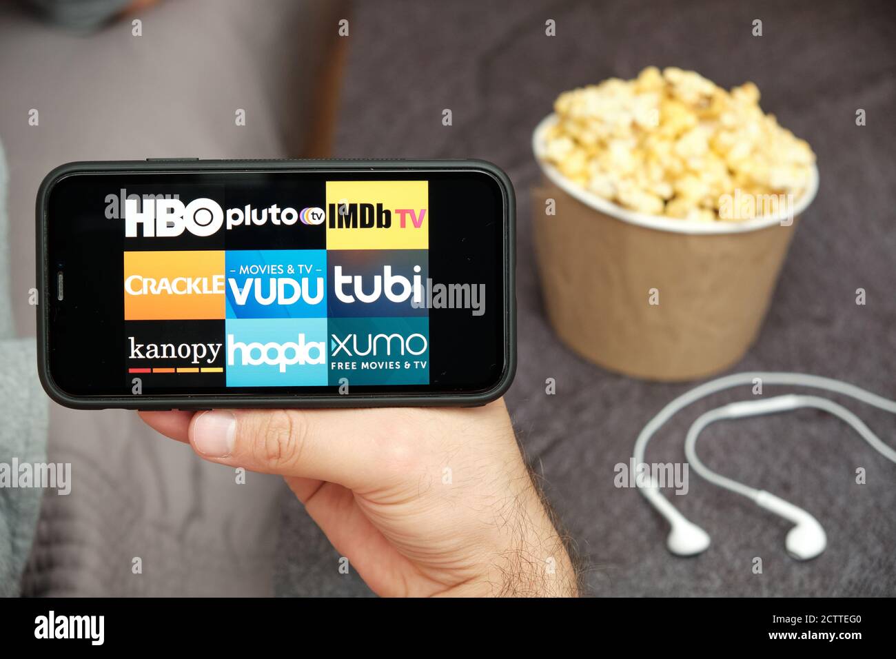 HBO, Plutón TV, IMDb TV, Crackle, Vudu, tubi, kanopy, hoopla, xumo logo en  la pantalla del teléfono móvil con palomitas de maíz y monodosis de Apple  en el fondo Fotografía de stock -