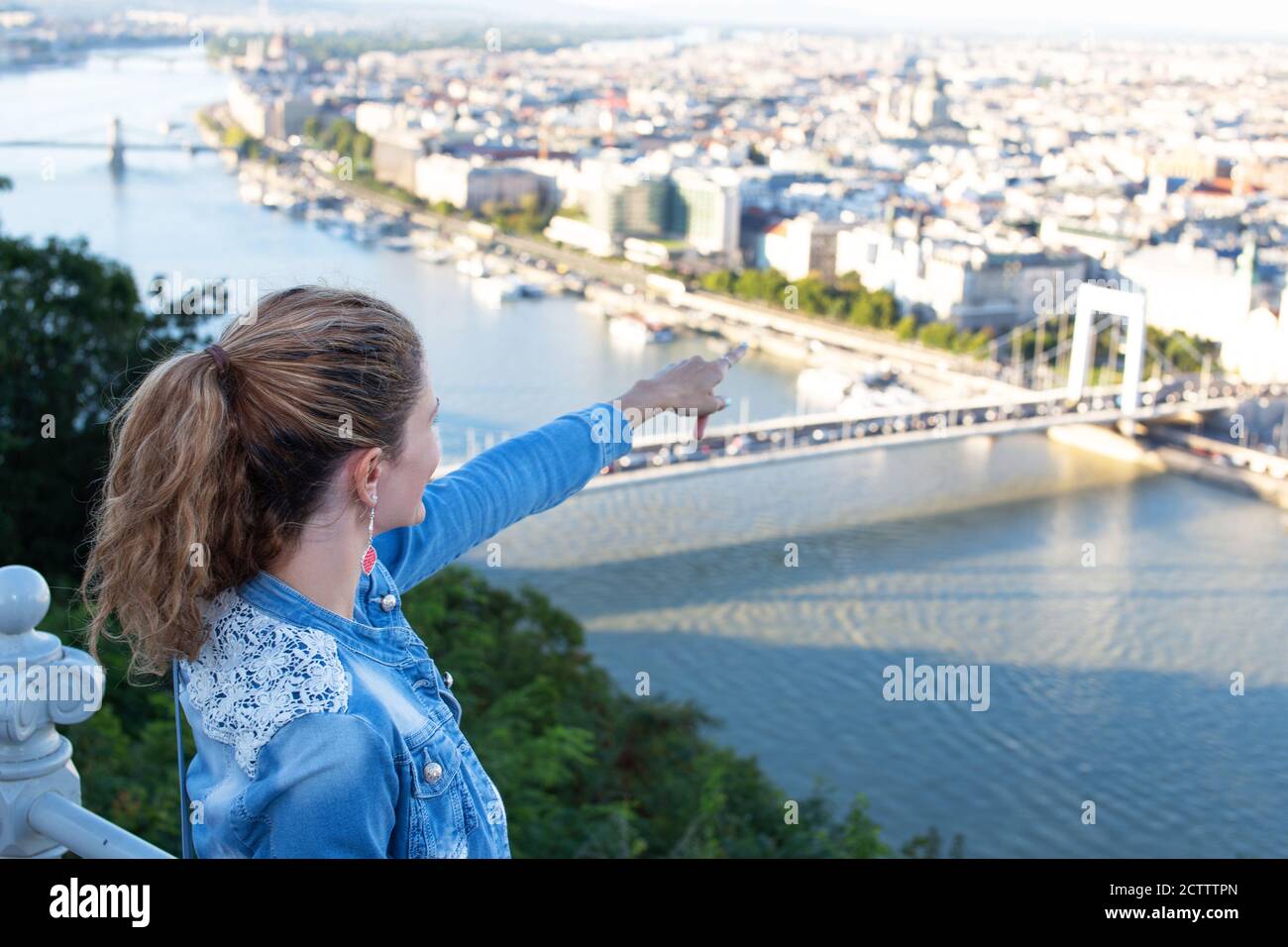 Mujer joven que señala a los destinos de la ciudad desde arriba, turismo, Budapest, Hungría Foto de stock