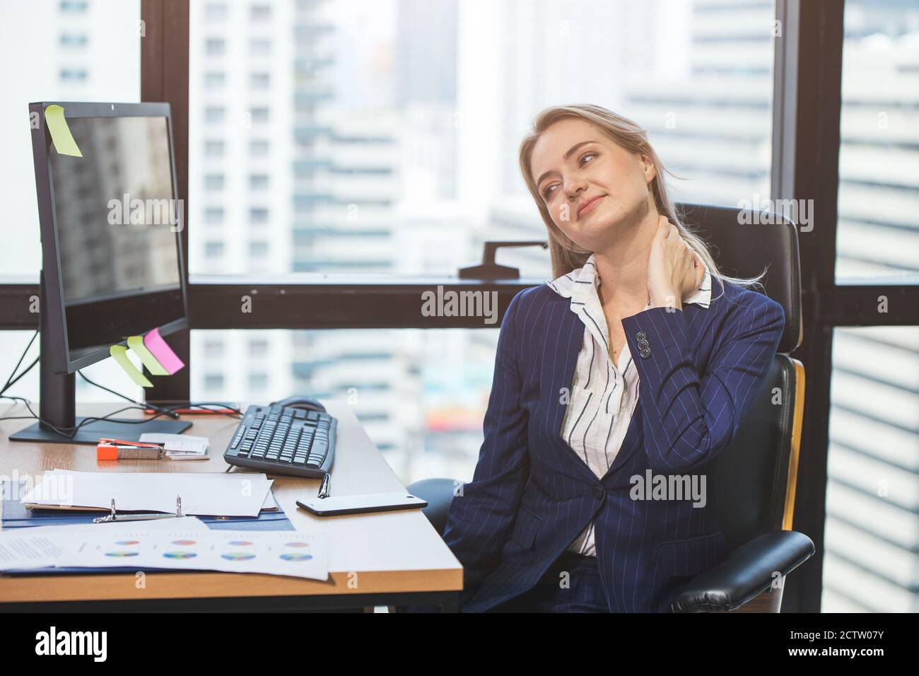 Mujer de negocios dolor de cuello de largo trabajo duro en la oficina. Foto de stock