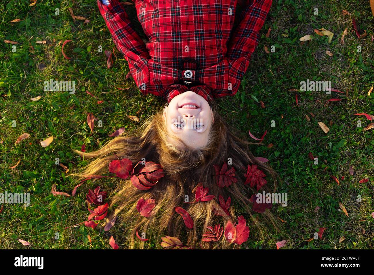 Una hermosa chica se encuentra en el suelo con hojas de otoño en su cabello. Foto de stock