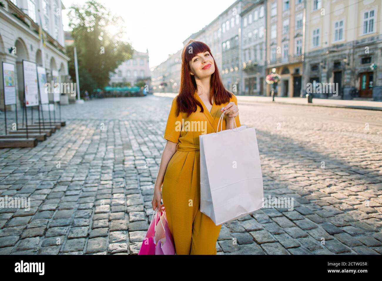 inercia Rey Lear No quiero Retrato urbano al aire libre de una joven elegante mujer de moda con ropa  de moda amarilla, disfrutando de su paseo y de las compras en la ciudad,  sonriendo Fotografía de stock -