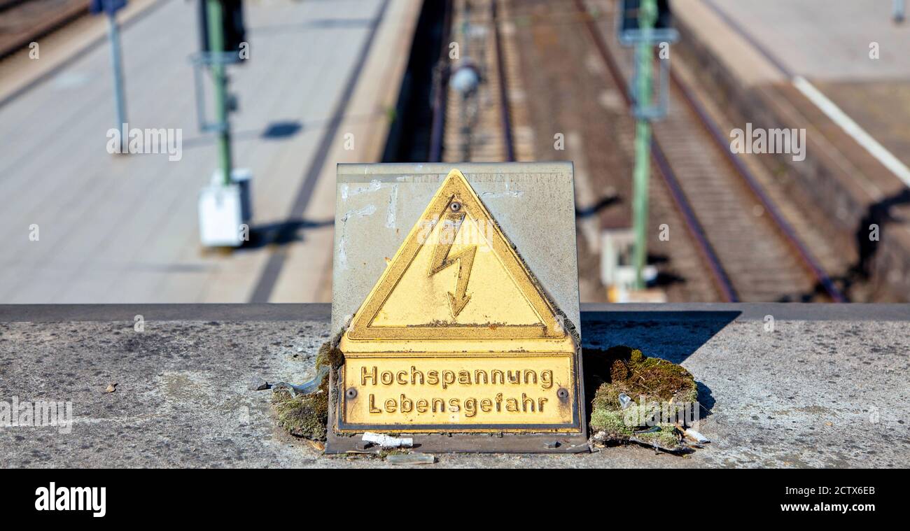 Instrucciones de seguridad. alemán señal amarilla de advertencia Hochspannung Lebensgefahr mostrando alta tensión - peligro para la vida en una estación de tren. Foto de stock