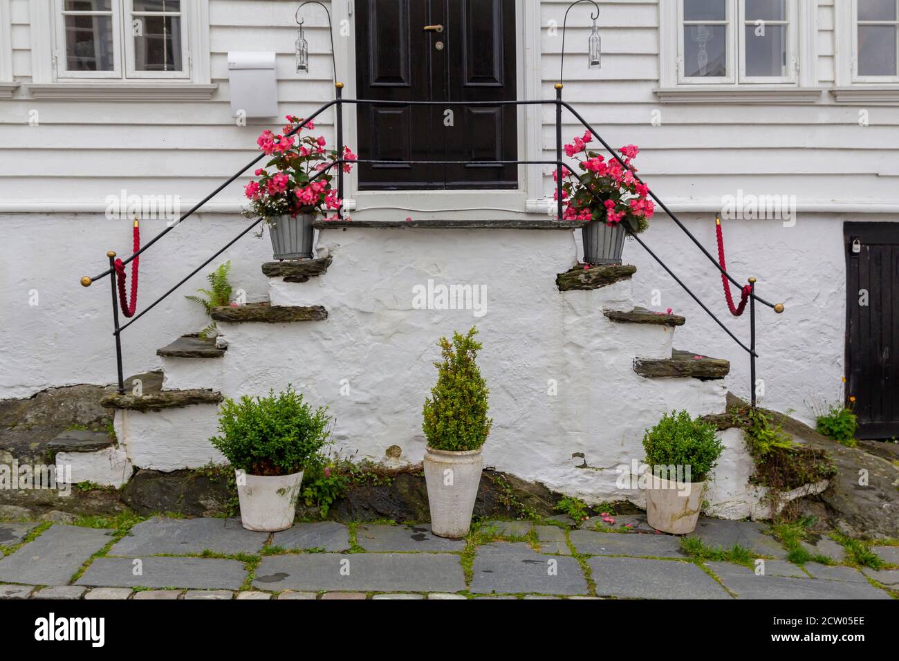 Entrada pintoresca con flores y plantas en una escalera blanca casa Foto de stock