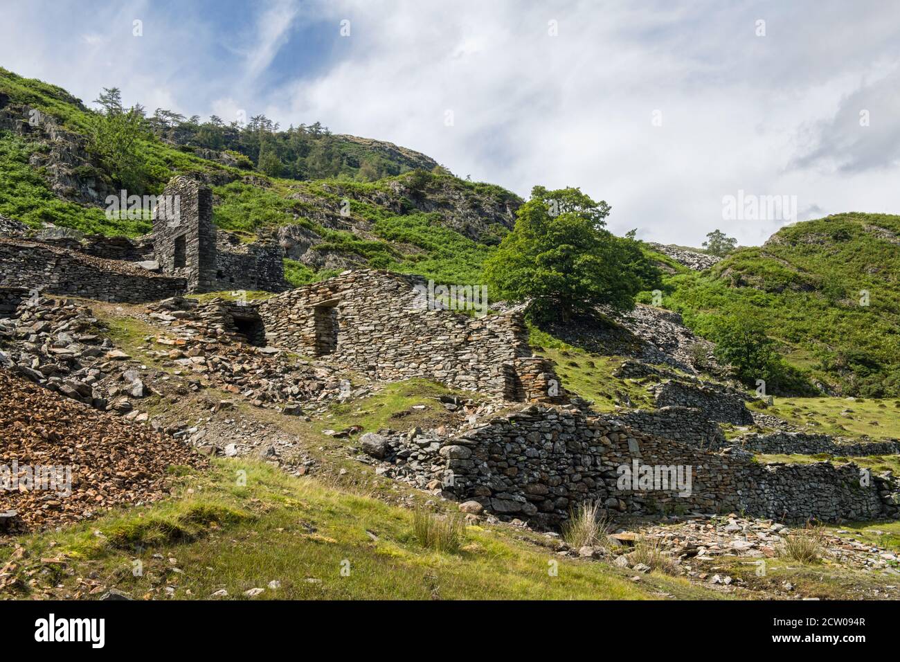 Los restos en ruinas de edificios a mitad de camino en la orilla del valle de Tilberthwaite en el Distrito de los Lagos. Estos bien pueden haber sido edificios de canteras. Foto de stock