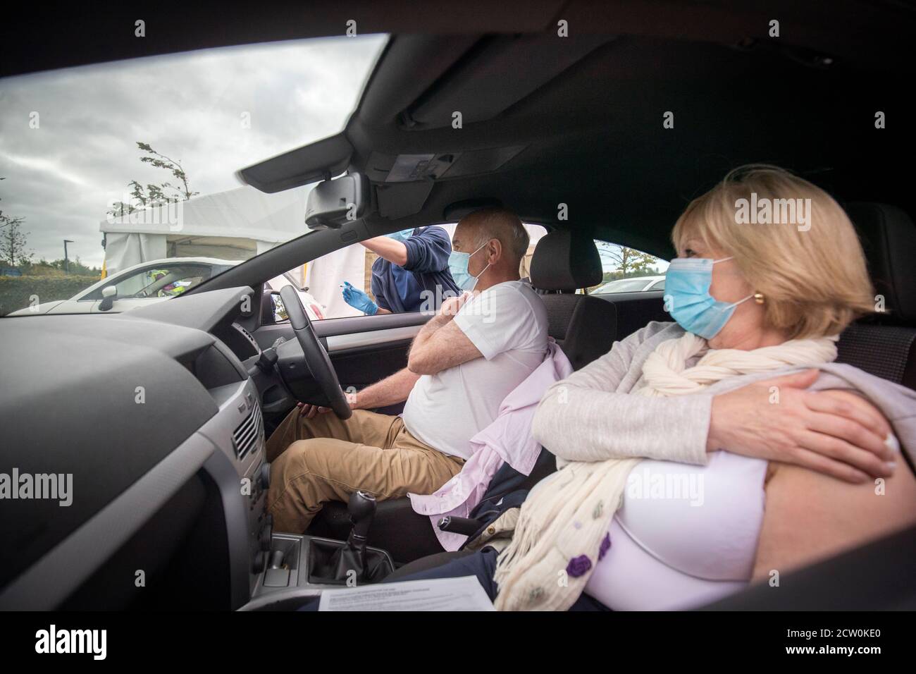 Un miembro del público recibe una vacuna contra la gripe sentada en su coche en una de las nuevas clínicas de la gripe de la pequeña Francia, Edimburgo. Foto de stock