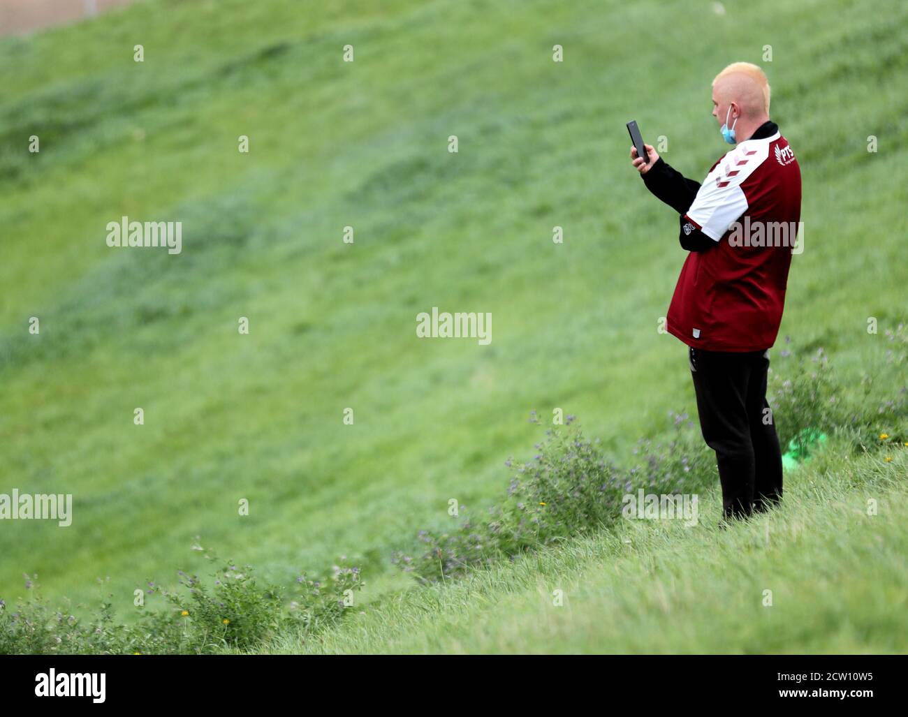 Un fan de Northampton observa a su lado calentarse desde una colina cerca del estadio Sixfields, Northampton. Foto de stock