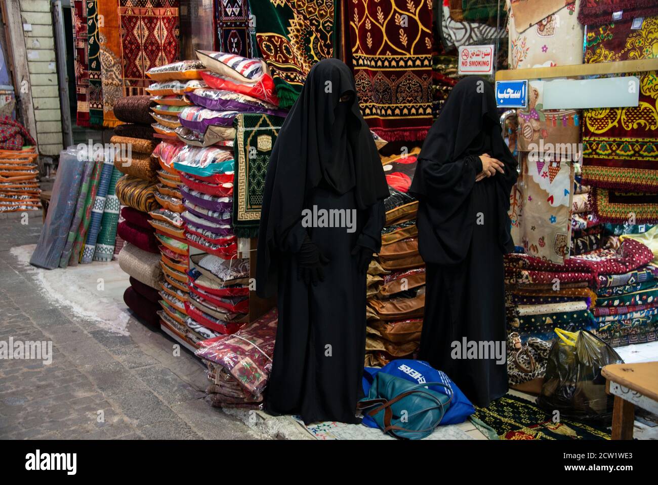Dos mujeres cubiertas en Jeddah, Arabia Saudita orando fuera de una tienda Foto de stock