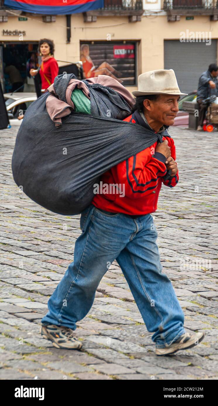 Quito, Ecuador - 2 de diciembre de 2008: Centro histórico. Hombre con  camisa roja y pantalones vaqueros azules con bolsa negra grande llena de  ropa en su espalda caminando o Fotografía de stock - Alamy