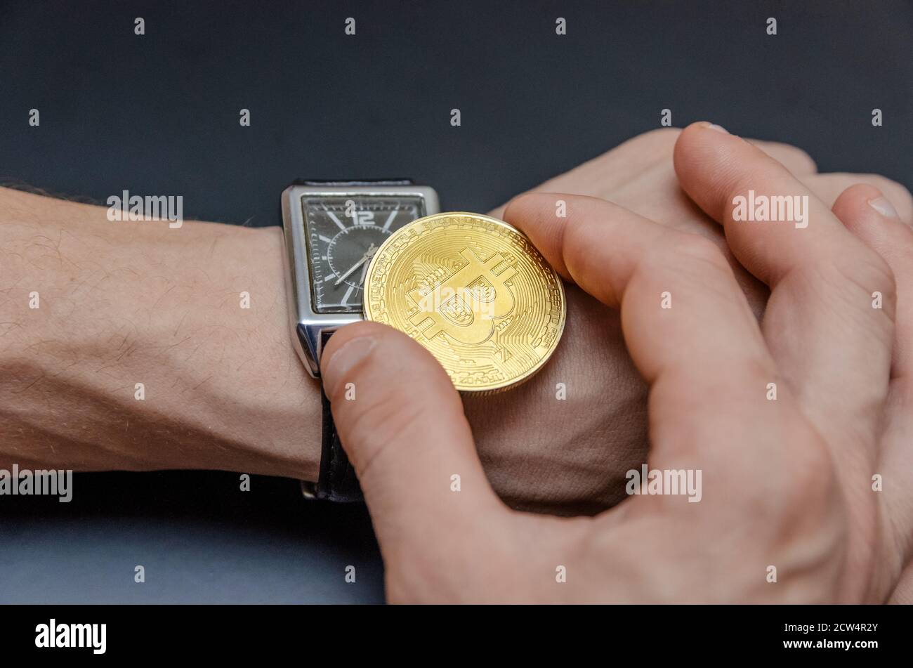Las manos de hombre joven fijando el reloj con un penique de oro bitcoin, el concepto del tiempo para actuar Foto de stock