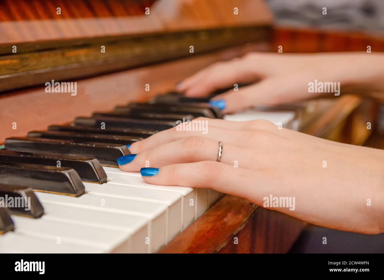 Manos de una pianista con esmalte de uñas azul en las uñas de las teclas de  un piano. Niña tocando el piano Fotografía de stock - Alamy