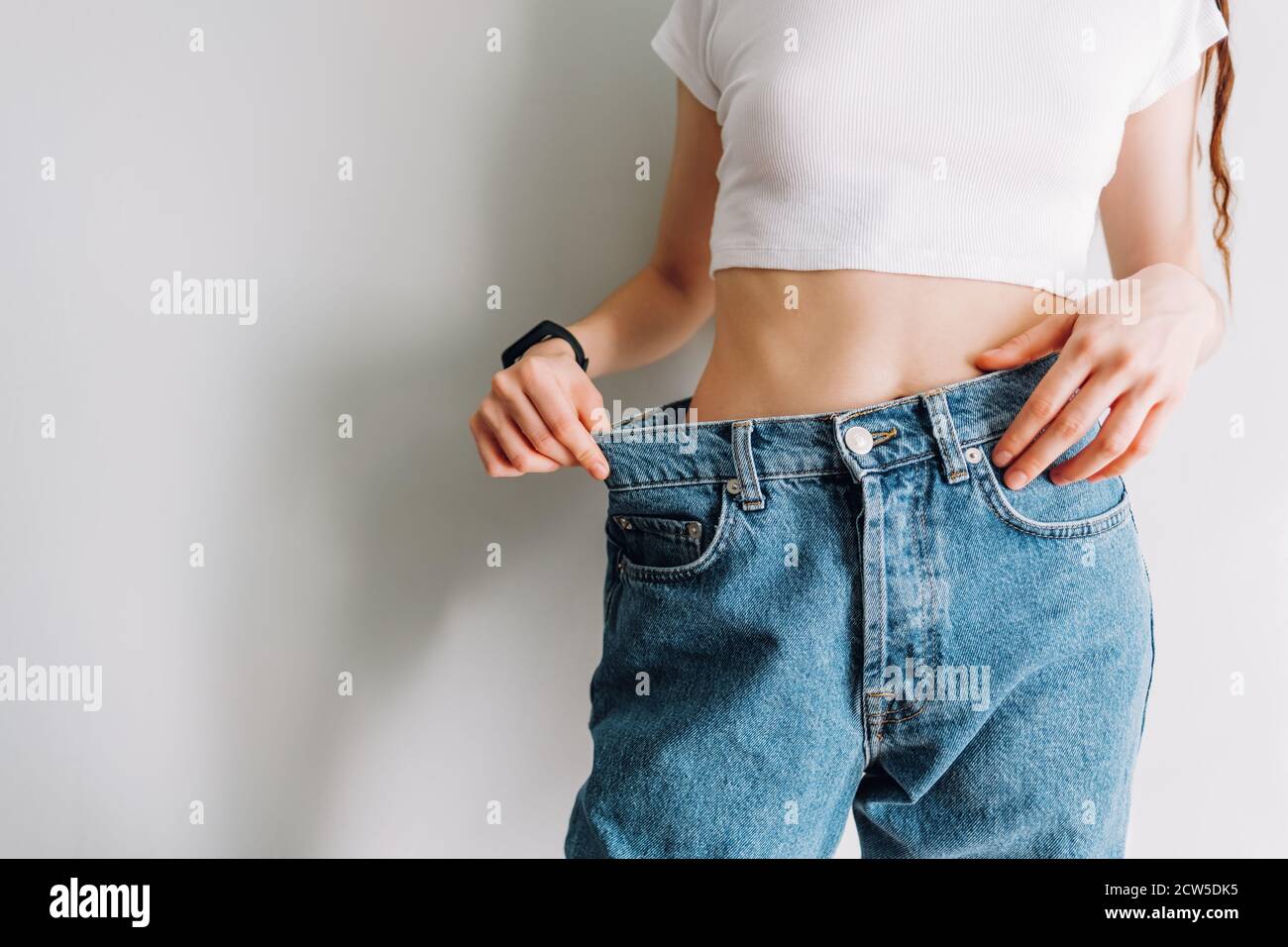 Mujer sostiene jeans en la mano, muestra una cintura delgada cuerpo  femenino delgado en jeans grandes Fotografía de stock - Alamy