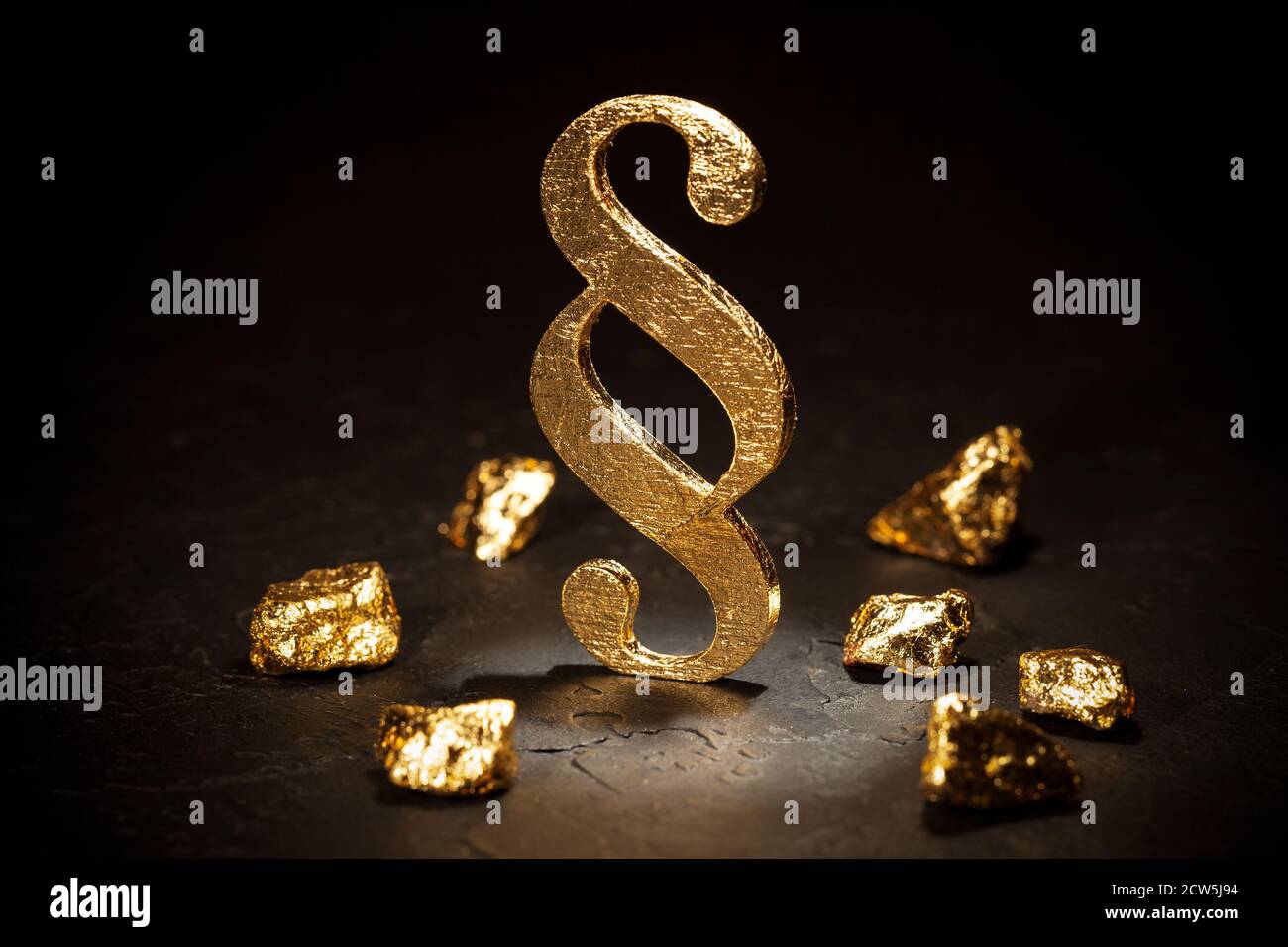 Signo de párrafo de oro y pepitas de oro sobre fondo negro. Foto de stock