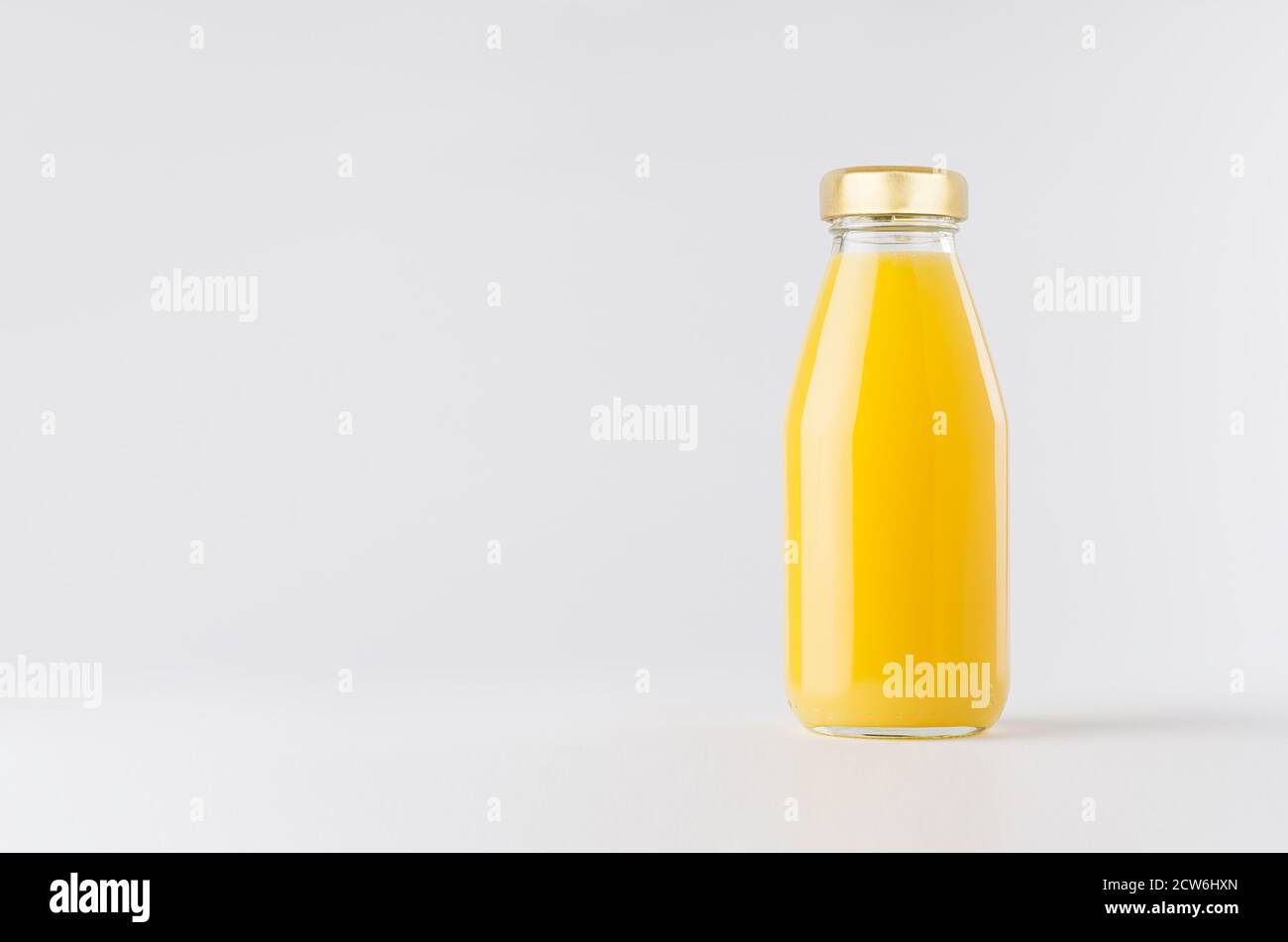 Zumo de naranja amarillo en botella de vidrio con tapón de oro simulado sobre fondo blanco con espacio de copia, plantilla para el embalaje, publicidad, diseño de productos, br Foto de stock