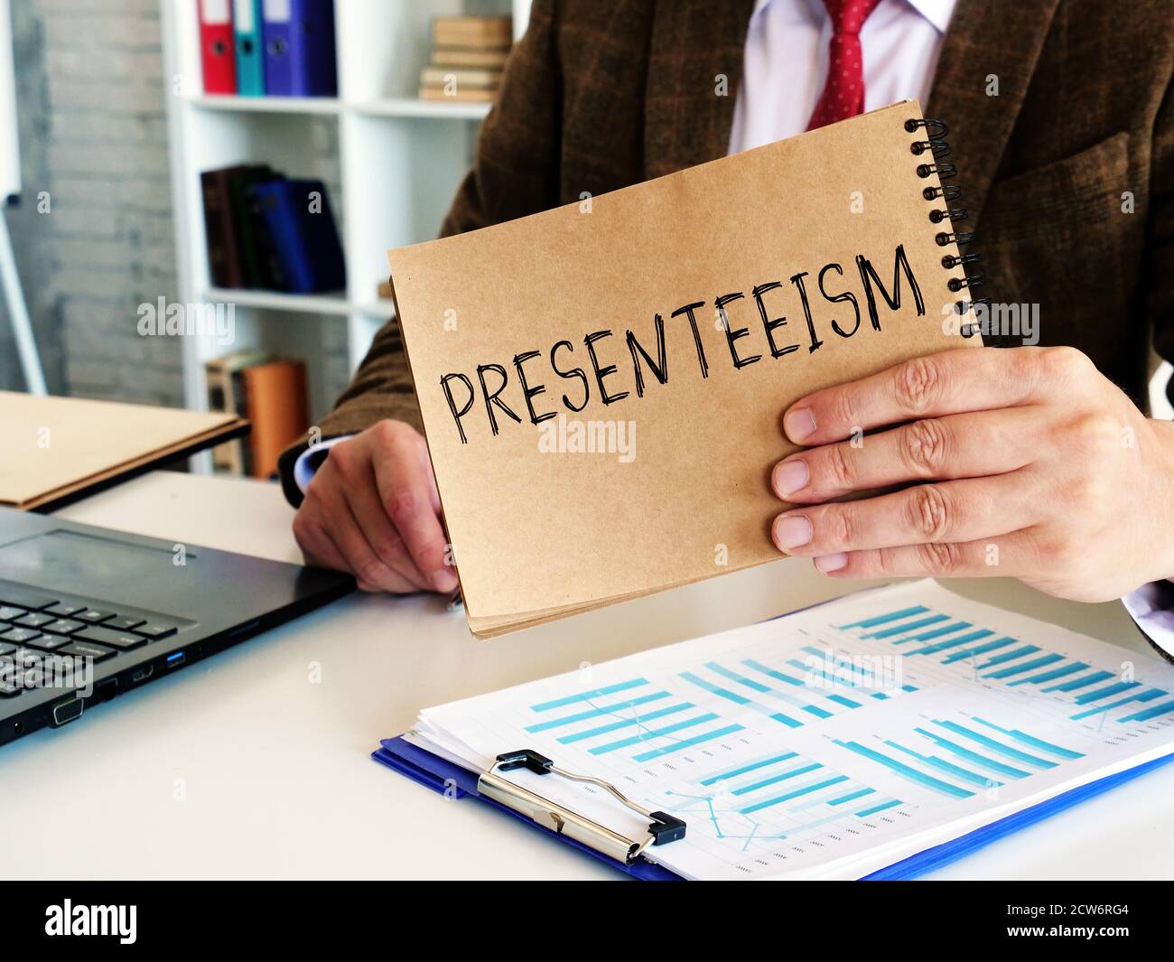 Concepto de presenteísmo. El empleado tiene un bloc de notas con la inscripción. Foto de stock