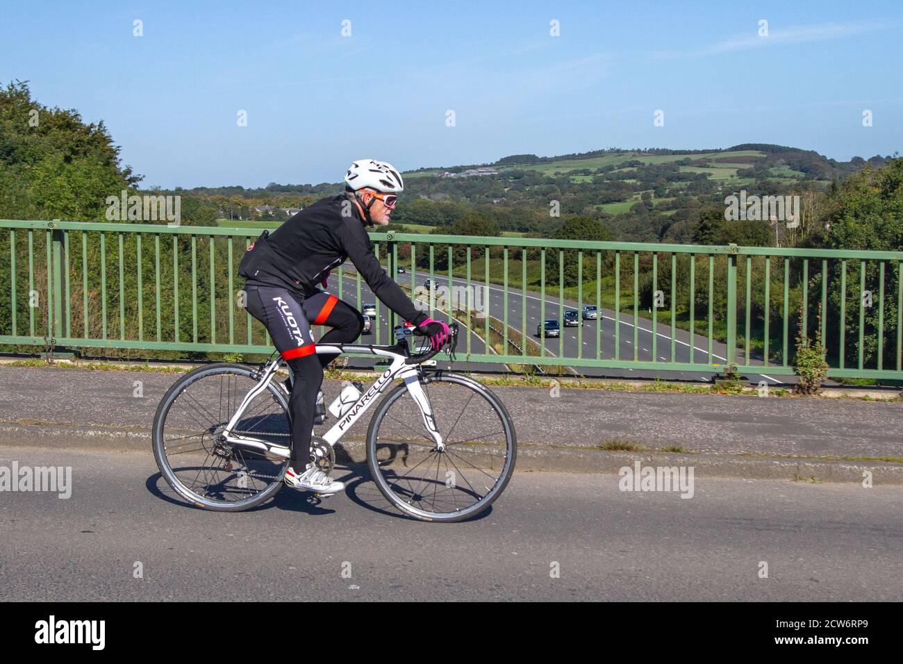 Hombre ciclista montar en blanco Pinarello Racing Bike razha Campagnolo  deportes bicicleta de carretera en el campo ruta de cruce puente de  autopista en la zona rural de Lancashire, Reino Unido Fotografía