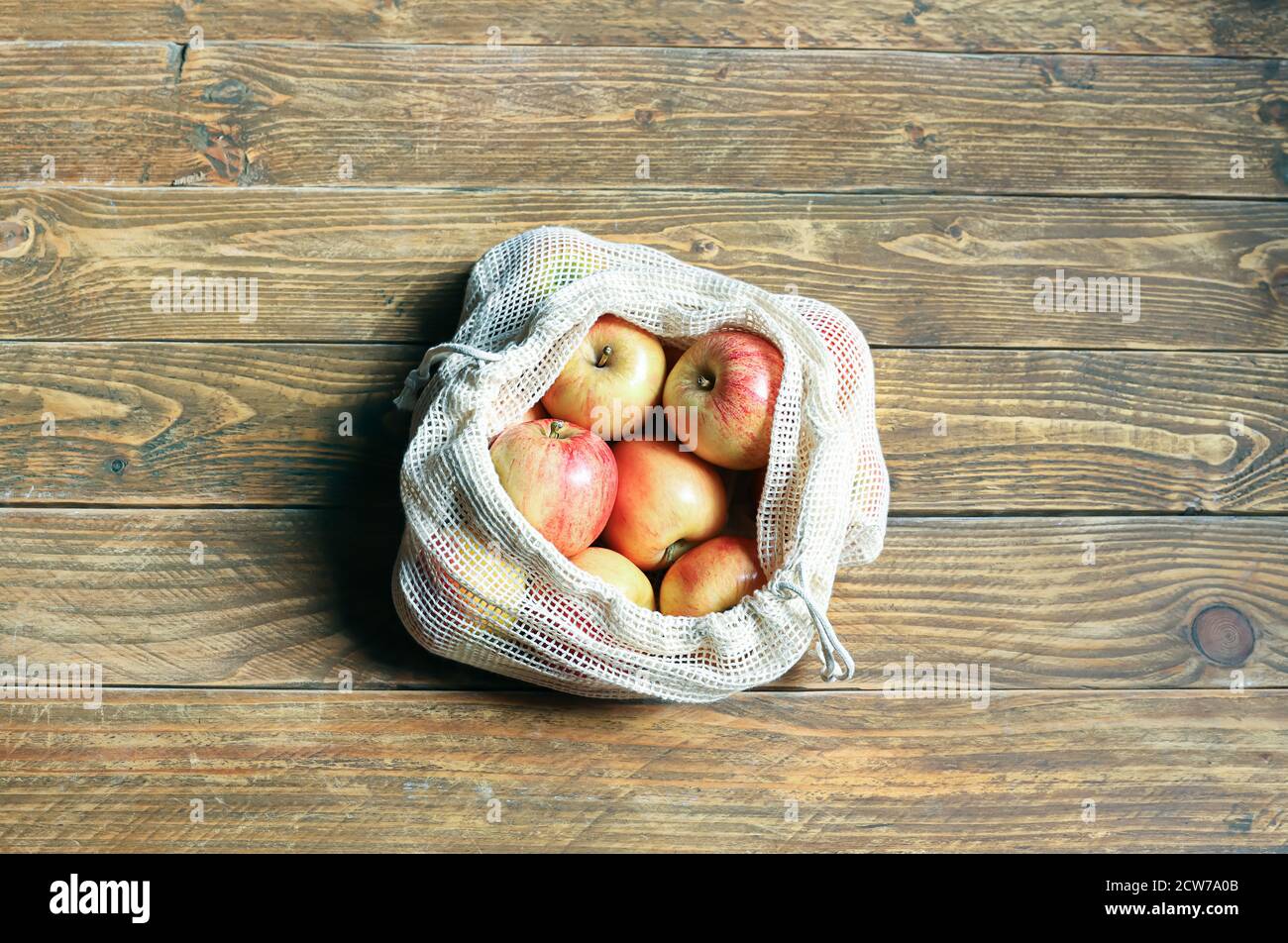 Manzanas orgánicas en bolsa de malla reutilizable ecológica sobre fondo de madera. Compras de alimentos sin paquetes. Concepto de cero residuos, estilo de vida libre de plástico. REU Foto de stock