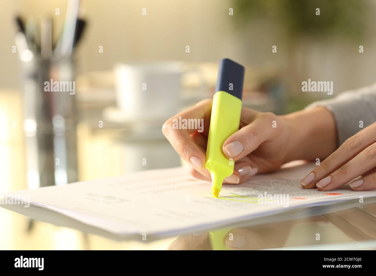 Primer plano de una mujer subrayando el texto del documento con marcador en un escritorio en casa Foto de stock