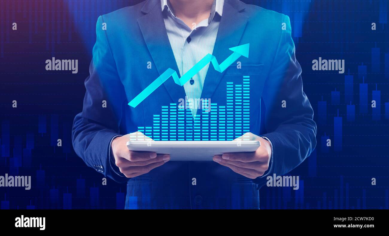 Businessman Holding Digital Tablet con creciente Gráfico Financiero, Fondo Azul Foto de stock