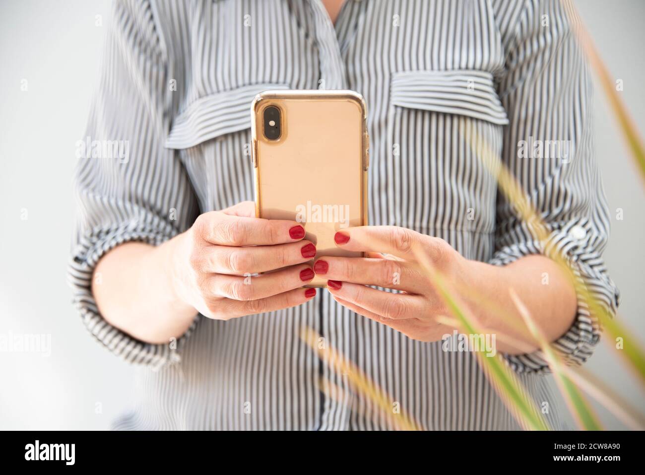 Imagen recortada de la mujer en la camisa inteligente con el teléfono inteligente interior Foto de stock