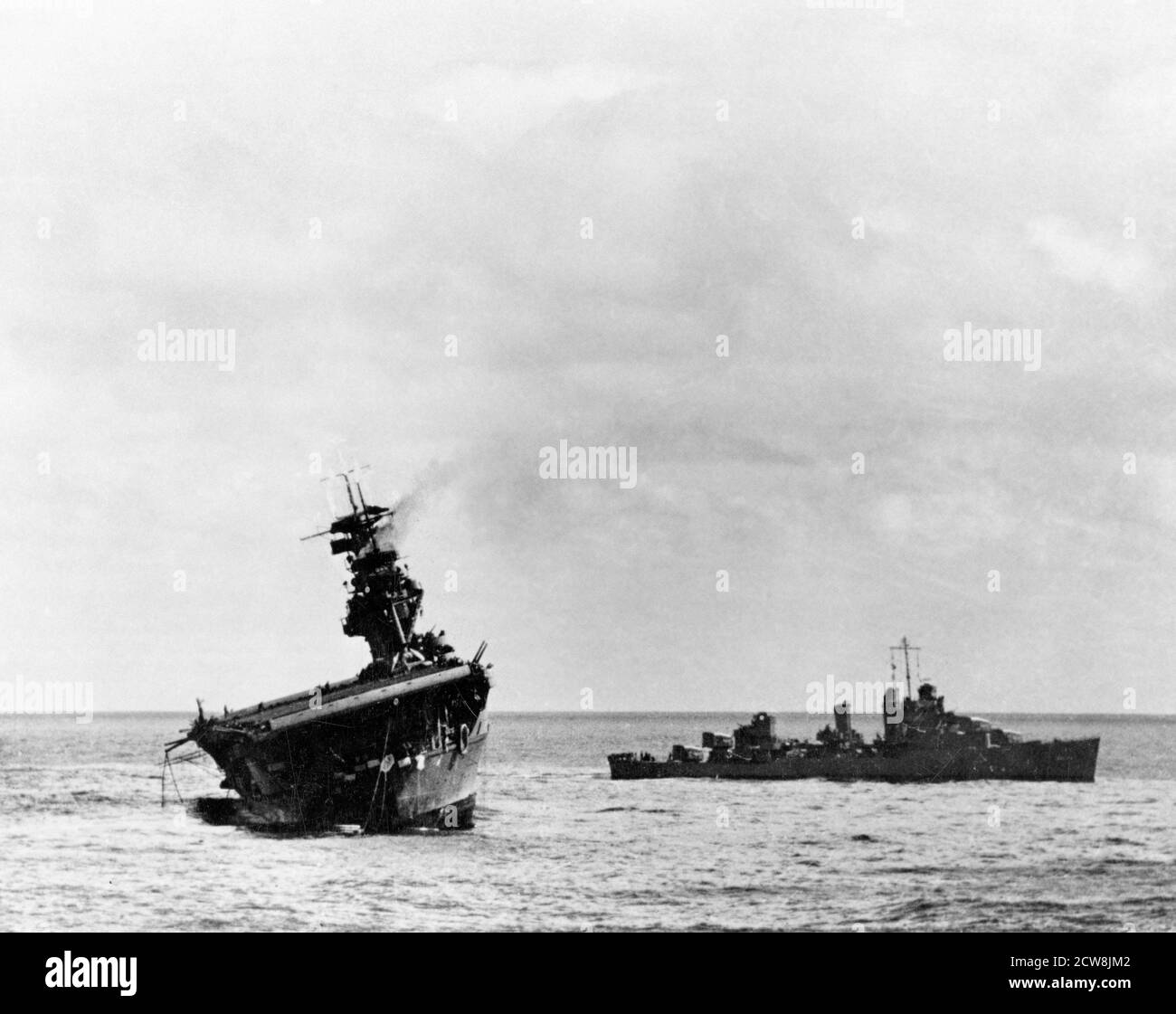 Batalla de Midway, junio de 1942. USS Yorktown (CV-5) siendo abandonada por su tripulación después de que fue golpeada por dos torpedos aéreos japoneses tipo 91, el 4 de junio de 1942. USS Balch (DD-363) está de pie a la derecha Foto de stock