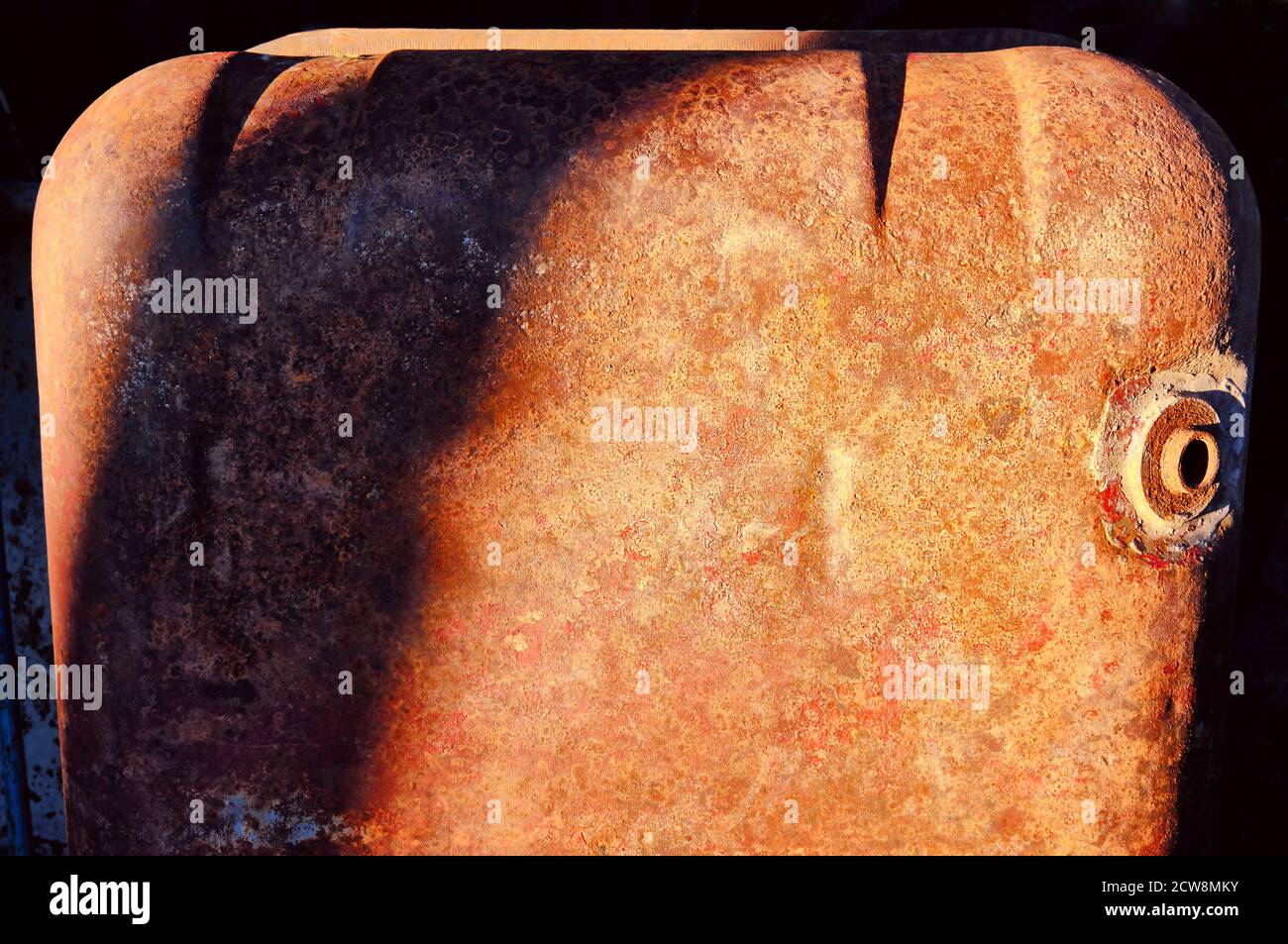 Textura de una superficie de metal oxidado con un agujero para drenaje de agua bajo luz solar suave Foto de stock