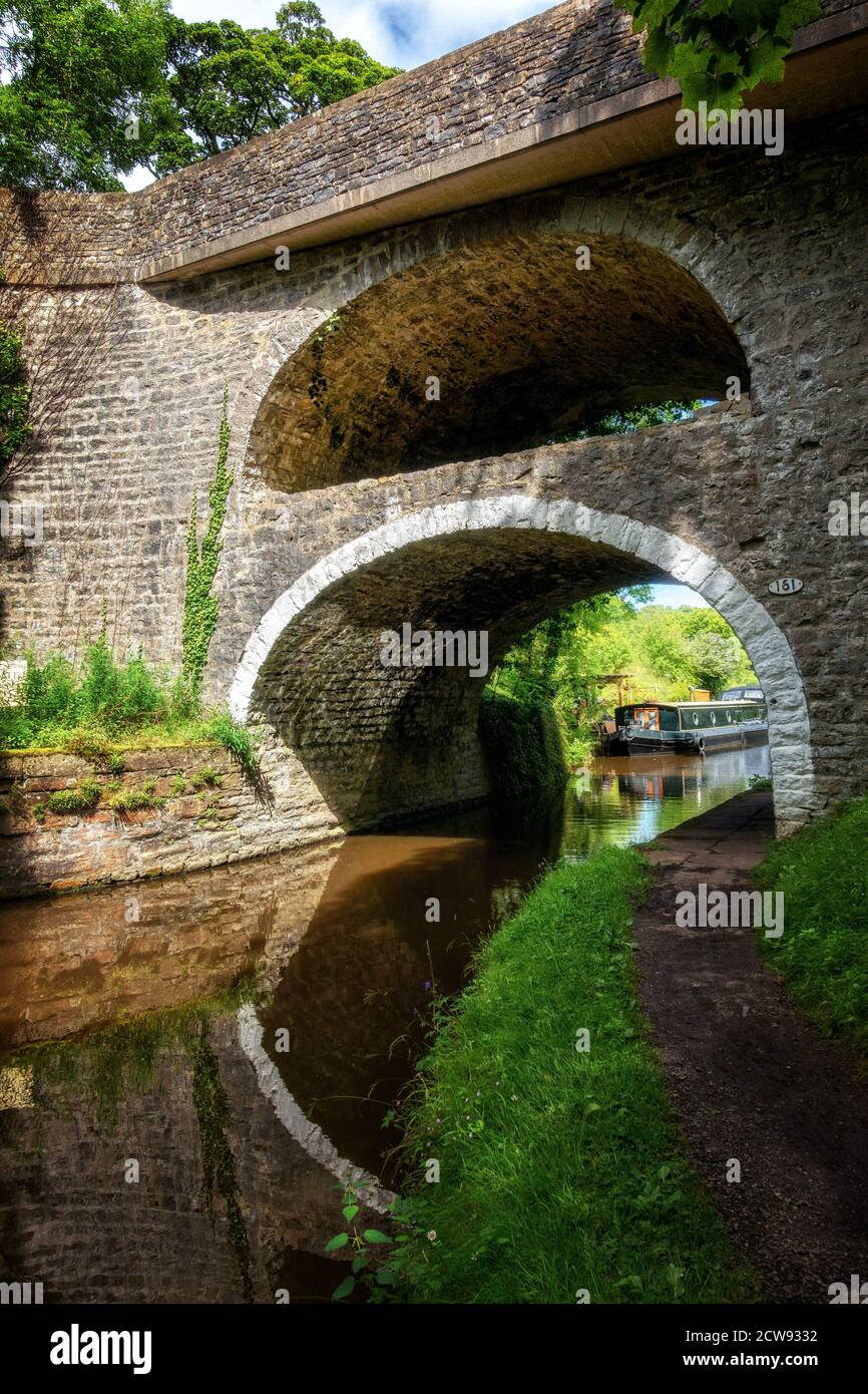 El puente del canal de doble arco no 161 en East Marton en el canal de Leeds Liverpool con la A59 en la parte superior, North Yorkshire, Reino Unido Foto de stock
