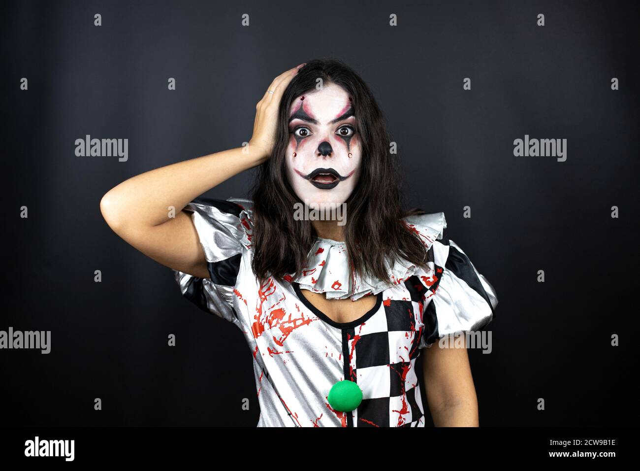 mujer en un traje de halloween payaso sobre fondo negro aislado poniendo  una mano en su cabeza sonriendo como lo había hecho algo olvidado  Fotografía de stock - Alamy