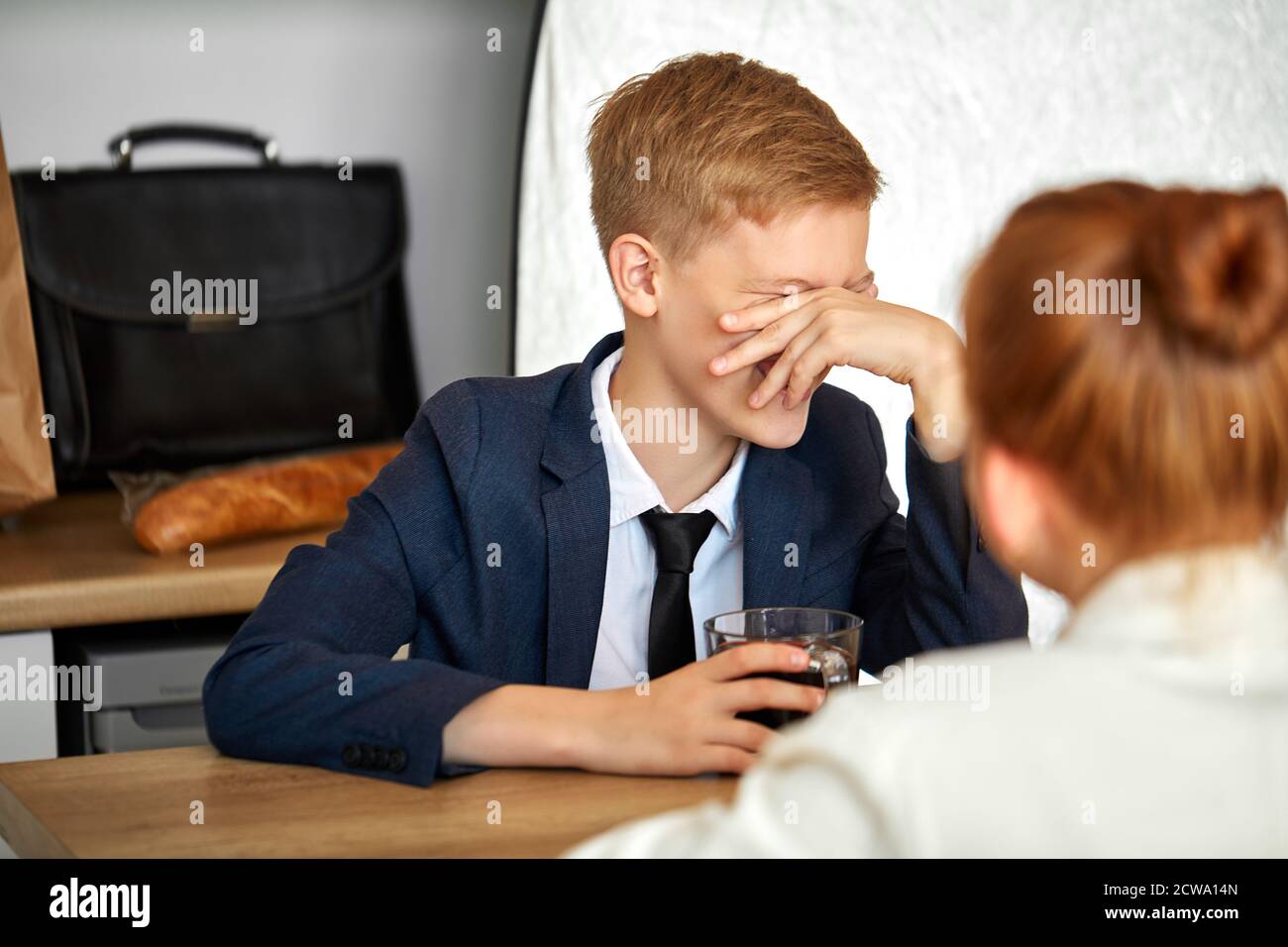 el niño se ríe, cierra la cara, se sienta con la chica de la pelirroja en  casa en la sala de estar, llevando ropa formal Fotografía de stock - Alamy