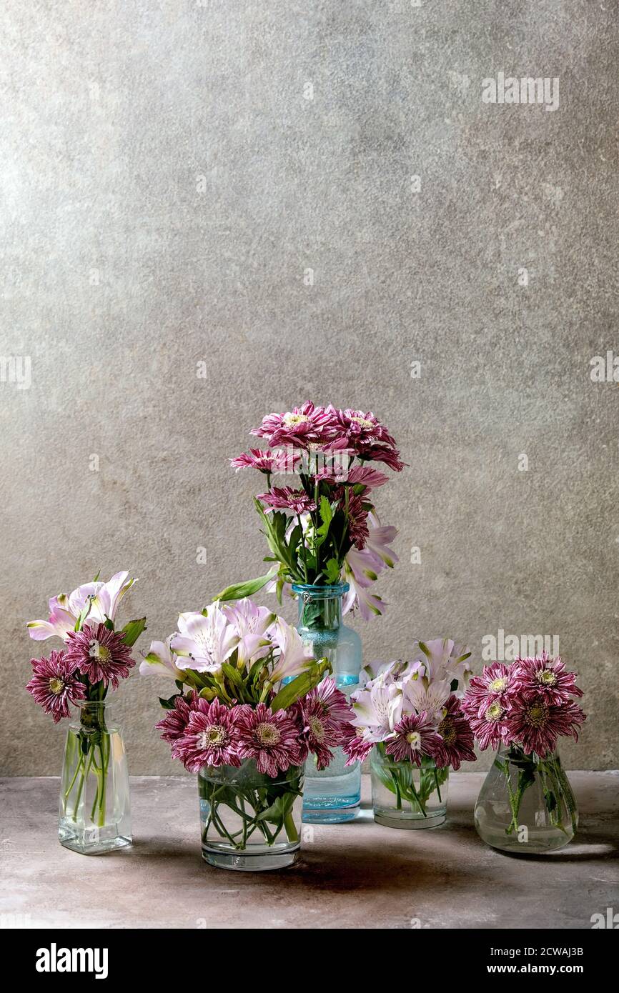 Grupo de botellas de vidrio y jarrones con flores decorativas