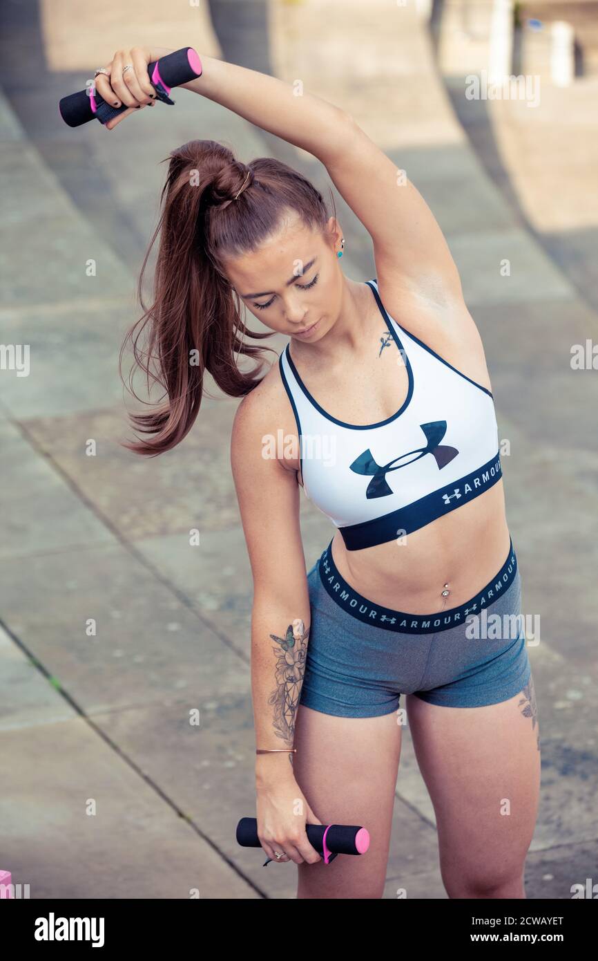 Una mujer joven que lleva ropa deportiva y que usa pesas para estirar las  manos Fotografía de stock - Alamy