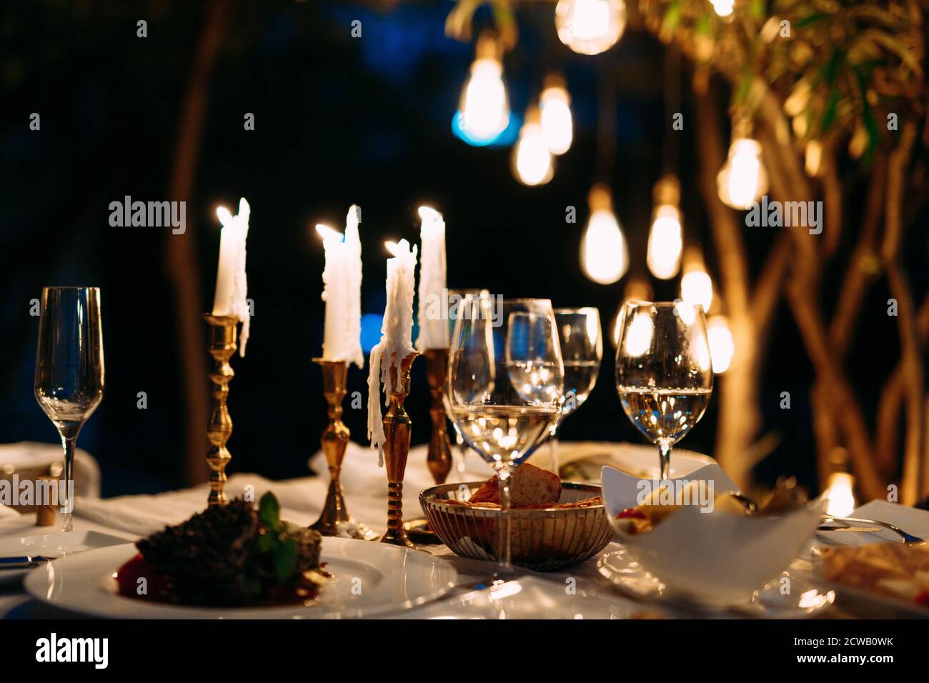 Cena romántica por la noche a la luz de las velas con vasos y ensaladas en  los platos Fotografía de stock - Alamy