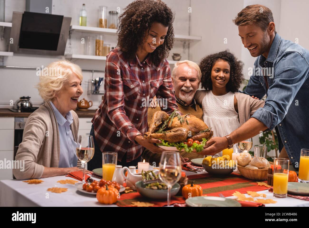Enfoque selectivo de la familia multiétnica que se encuentra cerca de turquía y acción de gracias cena en casa Foto de stock
