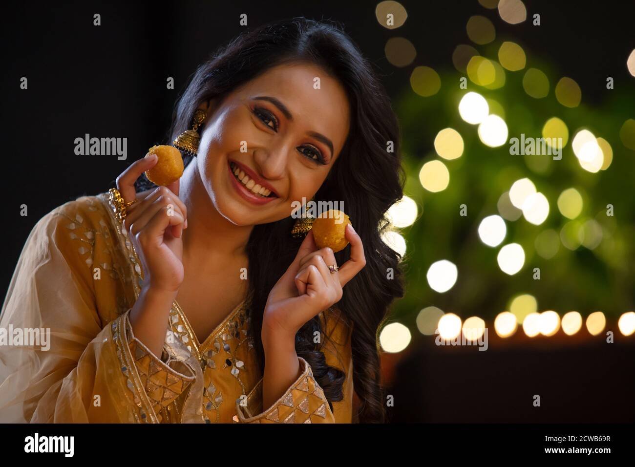 Mujer sonriendo con ladoos en sus manos en la ocasión De Diwali Foto de stock