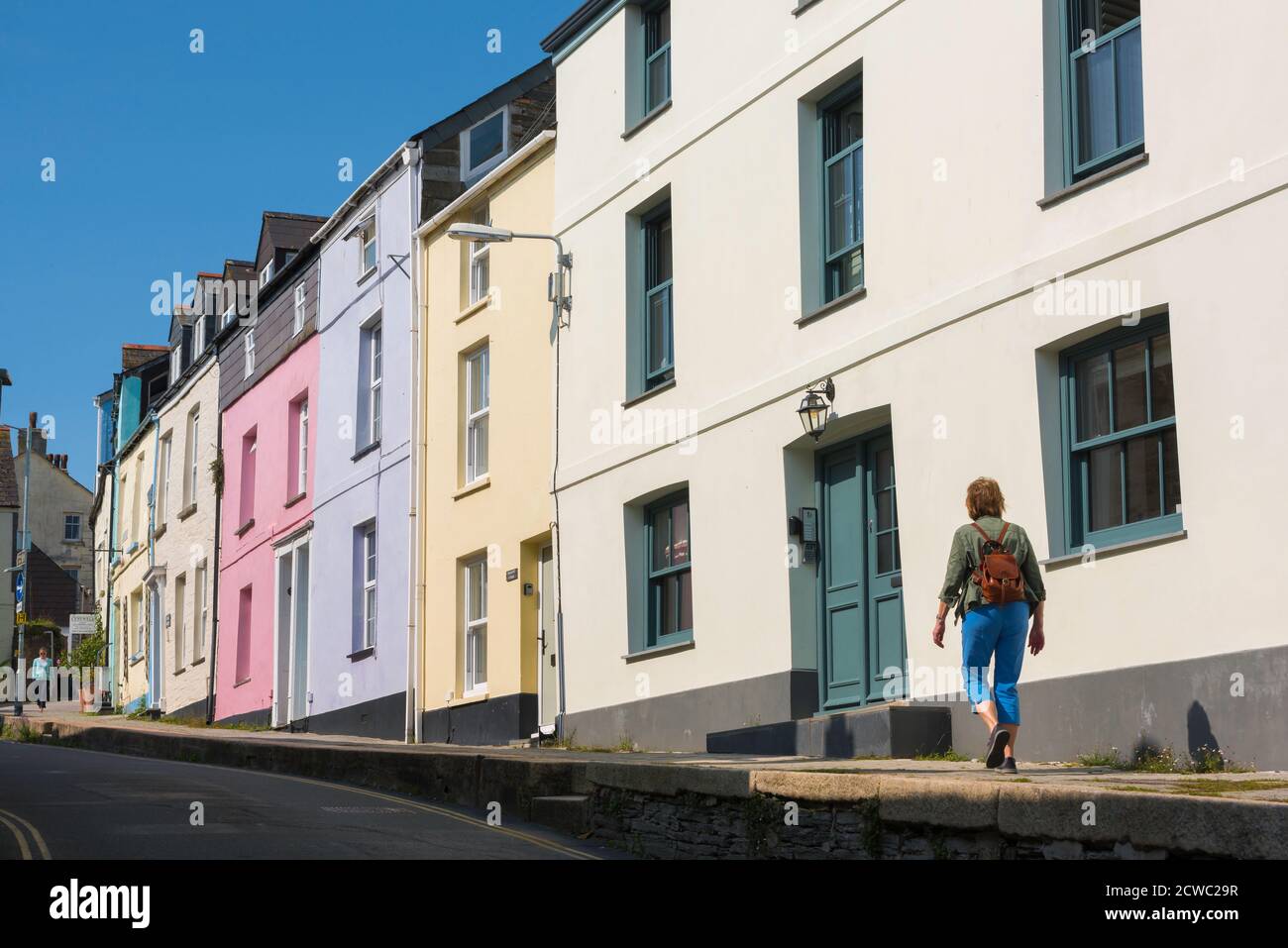 Concepto de vacaciones para mujer, vista trasera de una mujer soltera madura que lleva una mochila explorando una calle colorida en un barrio residencial, Reino Unido Foto de stock