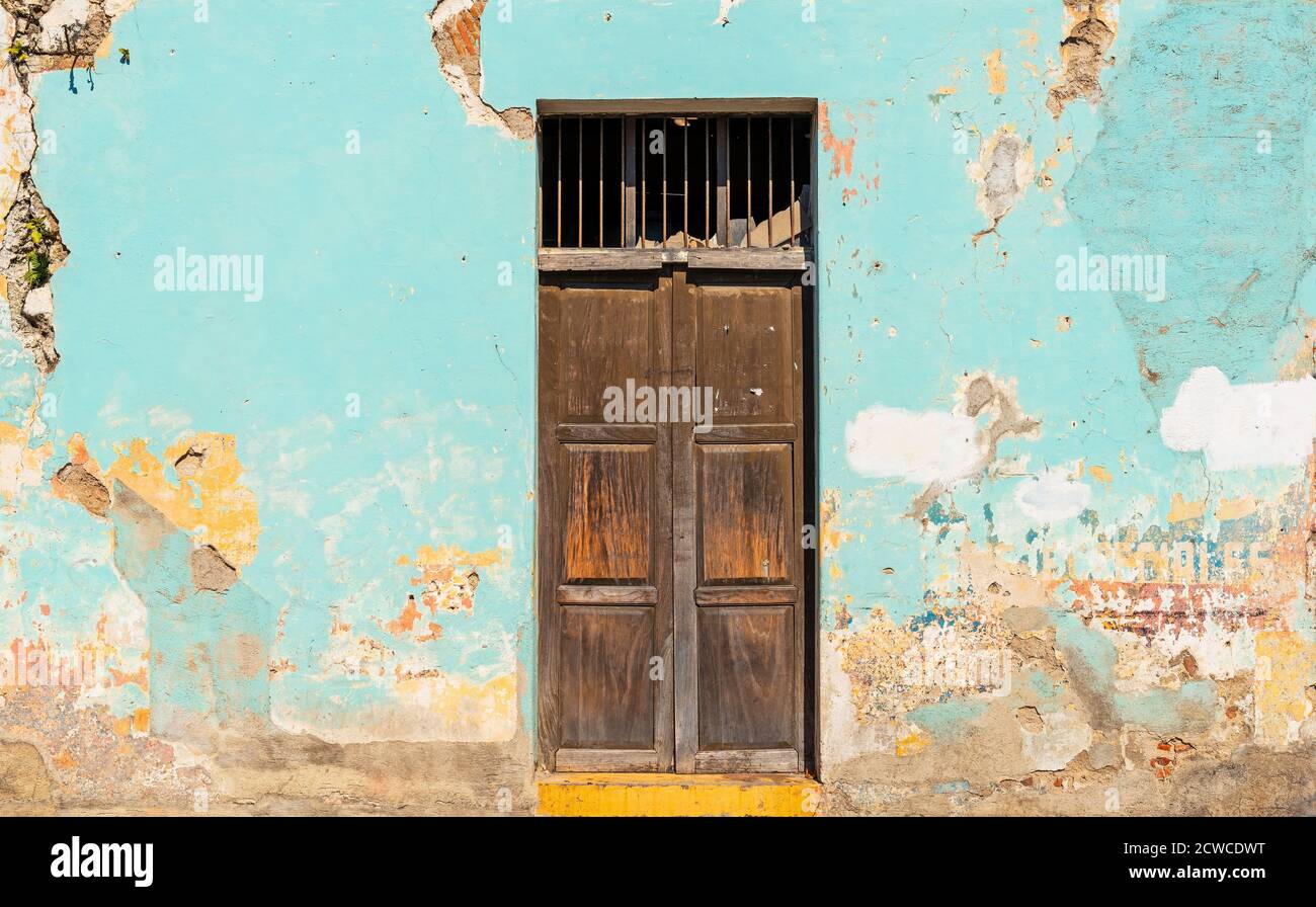 Puerta de madera de estilo colonial con pintura envejecida en la fachada, Antigua, Guatemala. Foto de stock