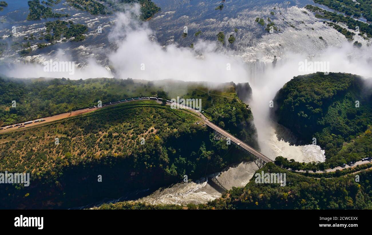 Impresionante vista panorámica aérea de las majestuosas y poderosas Cataratas Victoria (la cascada más grande del mundo) con puente histórico. Foto de stock