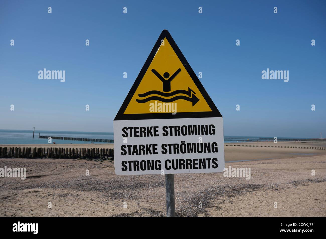 Fuerte señal de corriente en la playa con el mar azul en el antecedentes Foto de stock