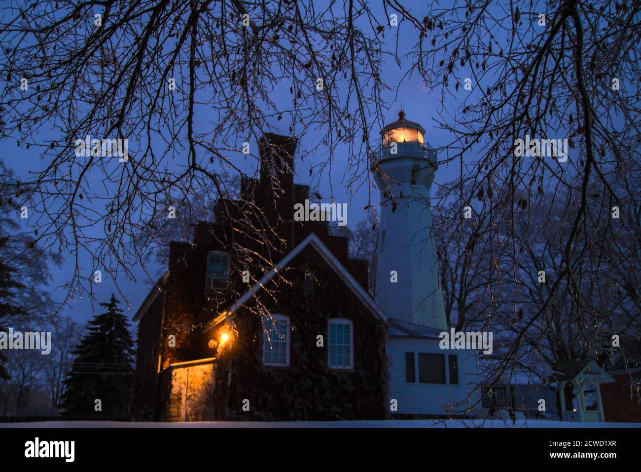 Port Sanilac, Michigan, EE.UU. - 12 de diciembre de 2013: Faro iluminado del Faro de Port Sanilac rodeado de caricles en una fría noche de invierno. Foto de stock