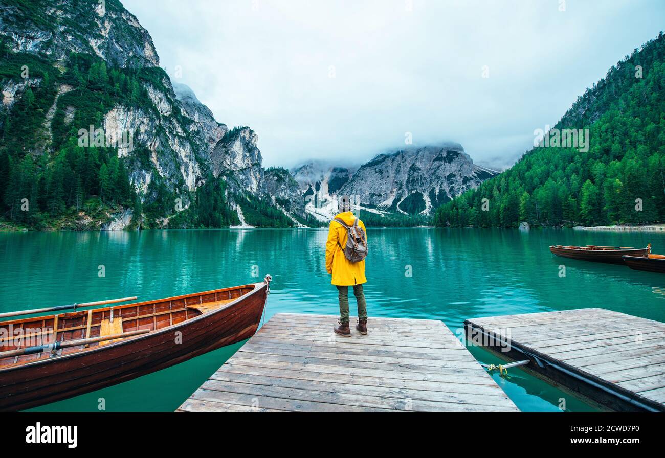 Historias de montaña. Feliz mochilero en unas vacaciones de lujuria. Hombre  con un chubasquero amarillo de pie frente al lago y disfrutando de la vista  Fotografía de stock - Alamy