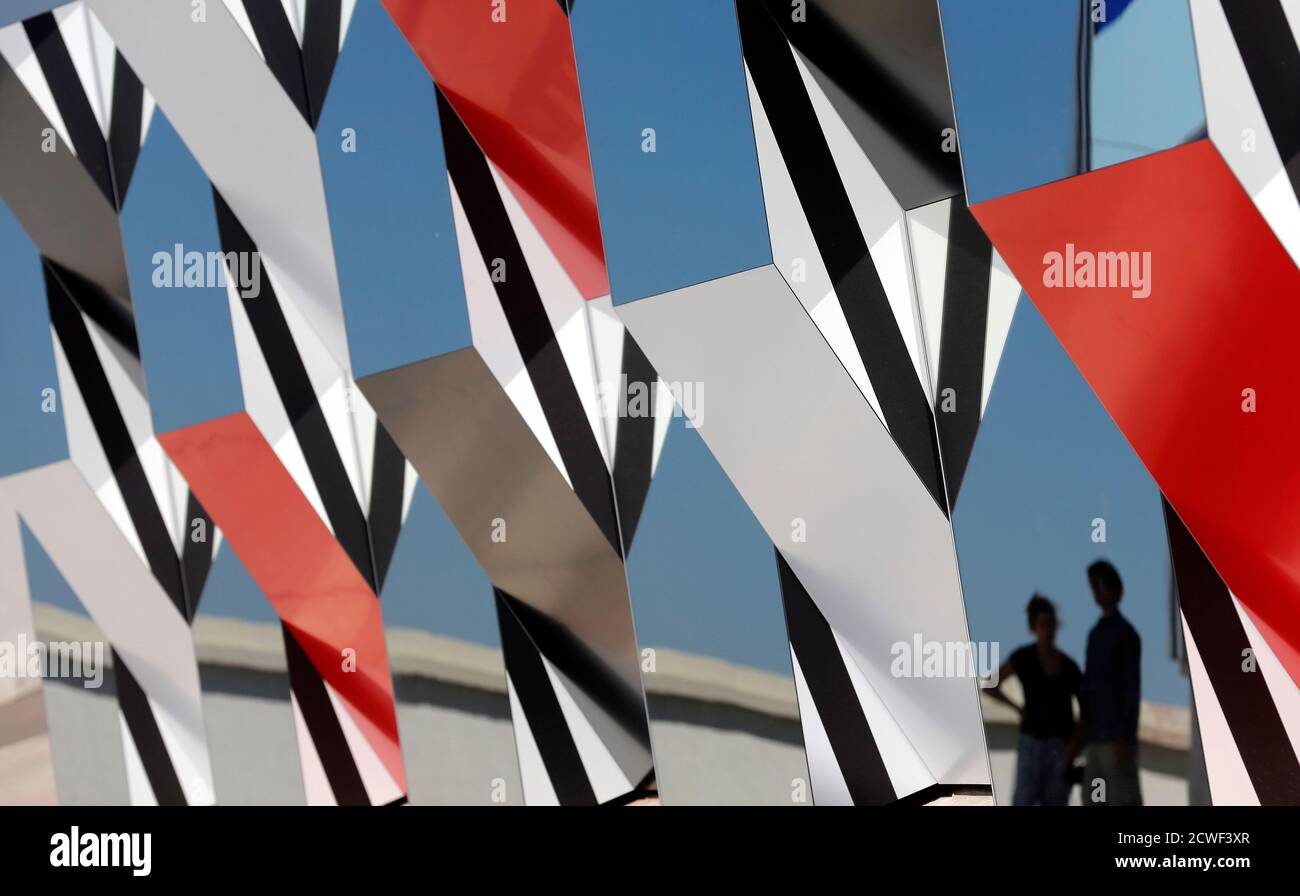 Visitors are reflected as they walk past a creation as part of the exhibition "Defini Fini Infini, Travaux in situ" by French artist Daniel Buren at the MaMo art center in Marseille September 12, 2014. The MaMo contemporary art center is installed on the restored rooftop terrace of Le Corbusier's 1947 Cite Radieuse (Radiant City) and created by French designer Ora-Ito. The exhibition will run until September 30, 2014. REUTERS/Jean-Paul Pelissier (FRANCE - Tags: ENTERTAINMENT SOCIETY TPX IMAGES OF THE DAY) Foto de stock