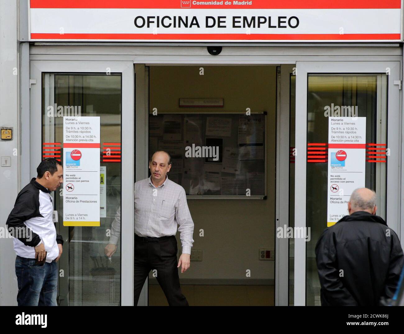 Un trabajador abre una oficina gubernamental de empleo donde la gente está  esperando afuera, en Madrid el 3 de marzo de 2015. El número de españoles  registrados como desempleados disminuyó en un