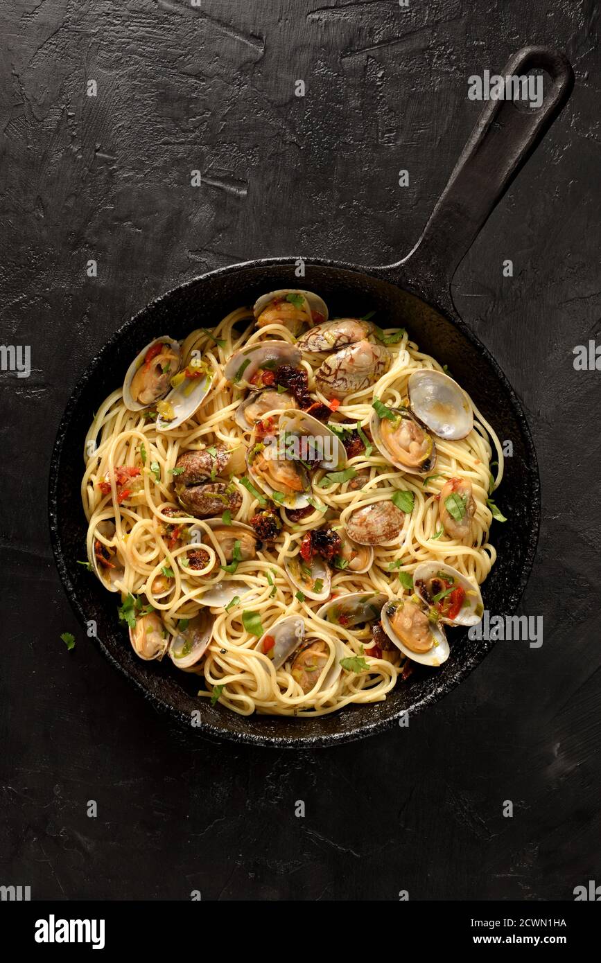 Pasta Spaghetti alle Vongole mariscos pasta con tomates secos y. puerro en  sartén negra sobre fondo negro vista superior espacio de copia Fotografía  de stock - Alamy