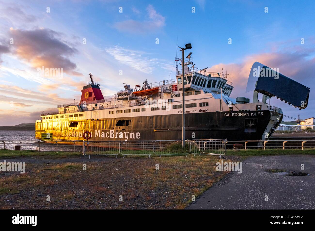 Calmac ferry el Caledonian preparándose para aterrizar y descargar vehículos en el puerto de Ardrossan en el Firth of Clyde al atardecer, North Ayrshire, Escocia. Foto de stock