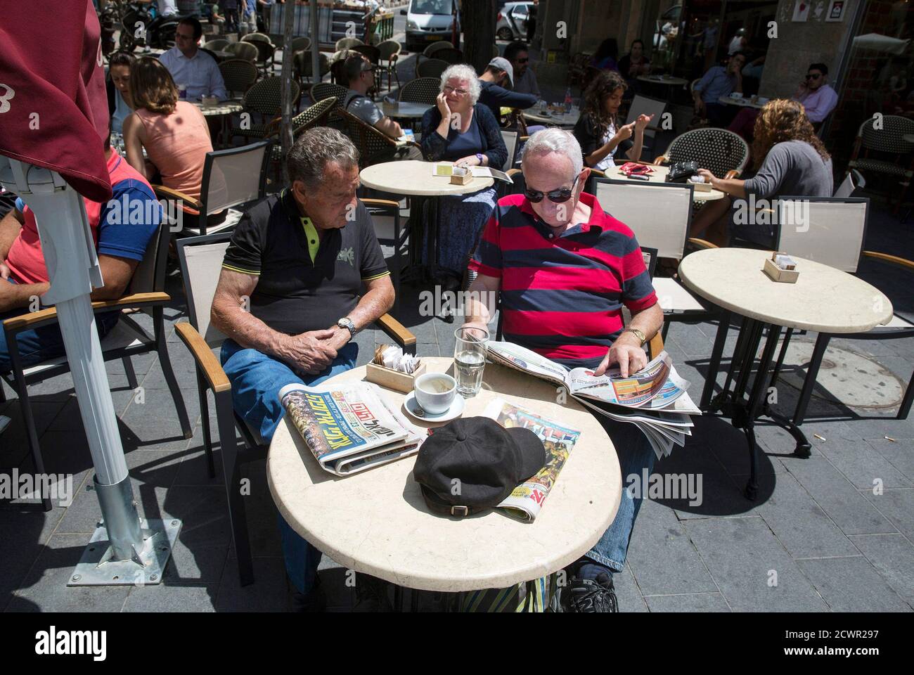 Los israelíes se sientan con una copia del periódico "Israel Hayom" (a la izquierda de la mesa) en un café en Jerusalén el 19 de mayo de 2014. REUTERS/Baz Ratner (JERUSALÉN - Tags: SOCIEDAD DE LOS MEDIOS de COMUNICACIÓN) Foto de stock