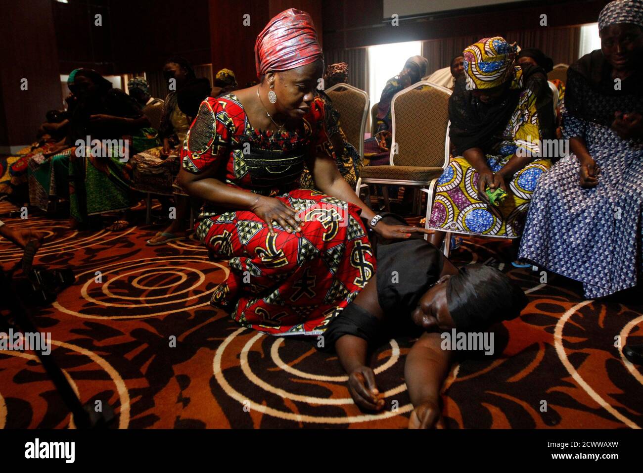 Una mujer acude a la madre de una de las más de 200 niñas secuestradas en la remota aldea de Chibok, después de que ella se rompió llorando durante una conferencia de prensa sobre las niñas en Lagos el 5 de junio de 2014. Varias madres de niñas que se estaban celebrando en?Nigeria?por el grupo militante?Boko Haram?se reunieron en?Lagos?el jueves, donde organizaciones no gubernamentales y un congresista del estado de EE.UU. Les ofrecieron terapia y apoyo. Boko Haram, un grupo militante que realizó una campaña para crear un estado islámico en la región, secuestró a 276 niñas de una escuela en Chibok el 14 de abril. REUTERS/Akintunde Akinleye (NIGERIA - Tags: DERECHO DEL CRIMEN POLIT Foto de stock