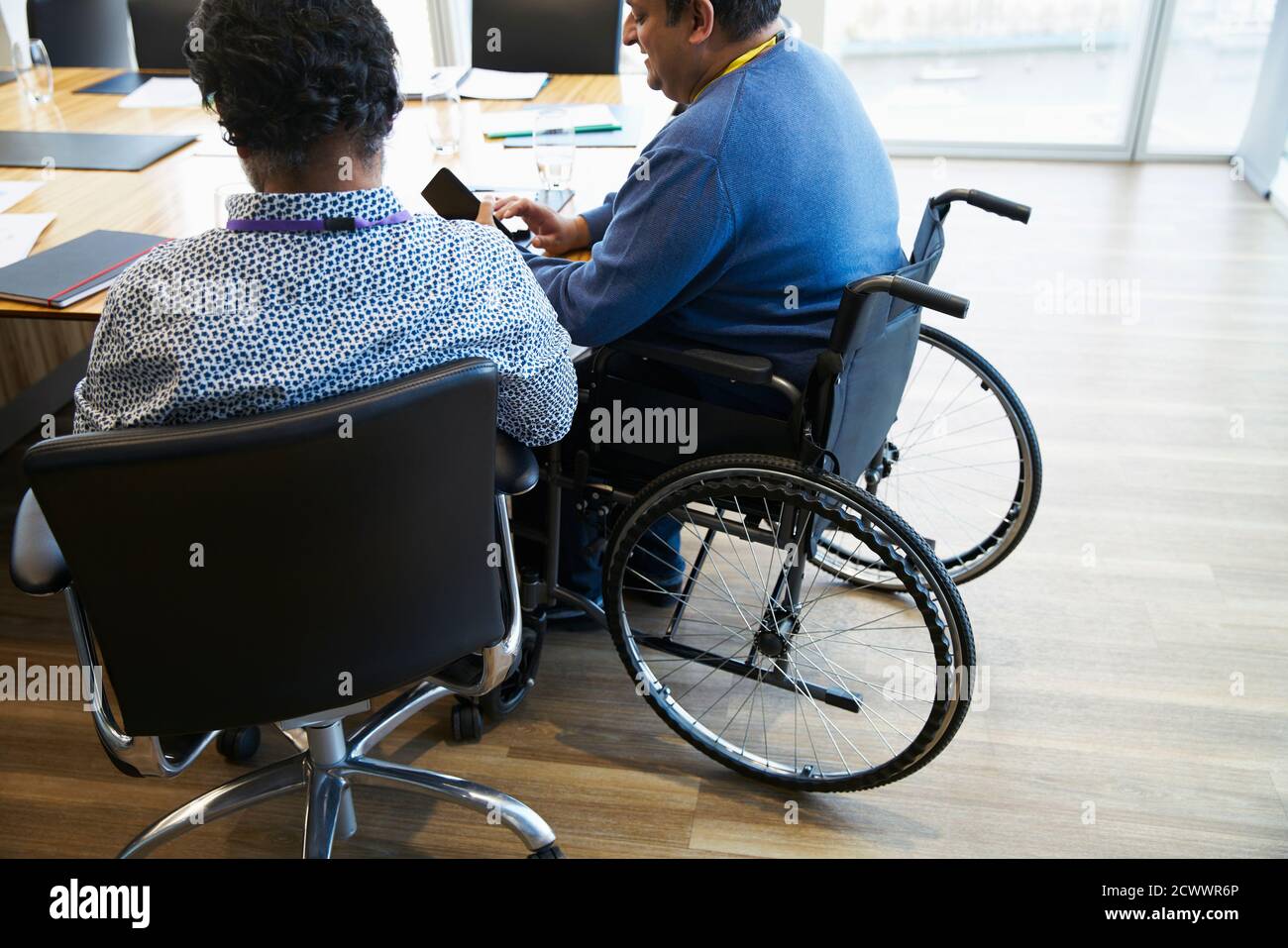 Hombre de negocios en silla de ruedas utilizando el teléfono inteligente en la sala de conferencias reunión Foto de stock