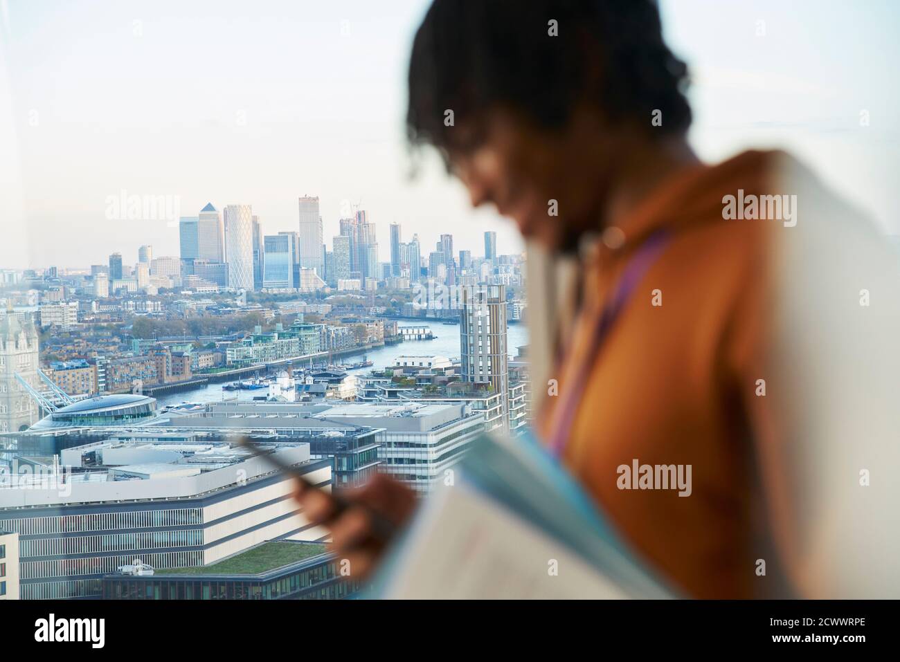 Hombre de negocios usando el teléfono inteligente en la ventana de gran altura, Londres, Reino Unido Foto de stock