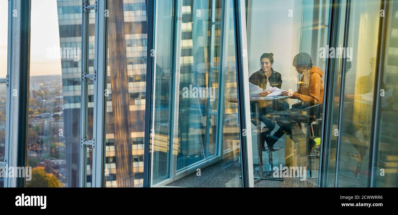 Gente de negocios que se reúne en una ventana de oficina de gran altura Foto de stock