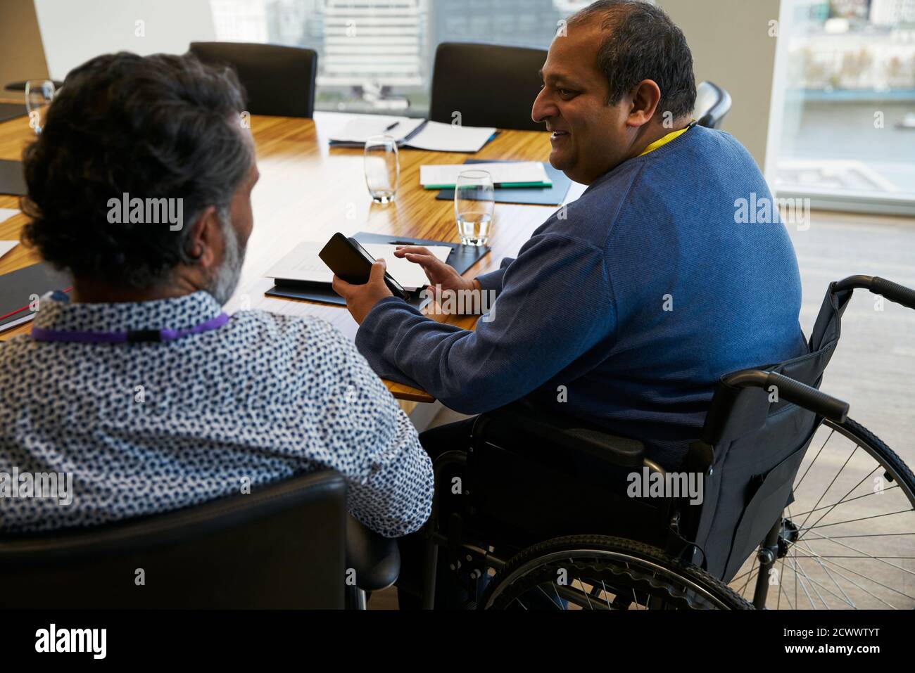 Hombre de negocios en silla de ruedas hablando con un colega en la reunión Foto de stock